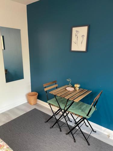 a table and chairs in a room with a blue wall at Willesden Green ROOMS in London