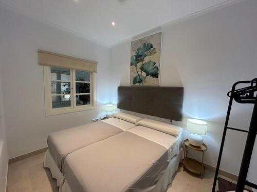 a white bedroom with a bed and a window at Olavide Premium Apartments in Seville