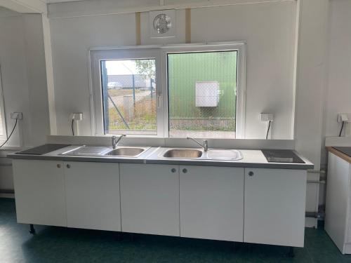 a white kitchen with a sink and a window at Ubytovna SDC in Valcha