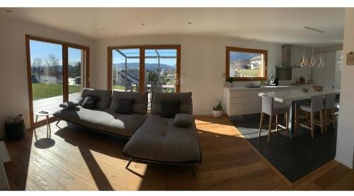 a living room with a couch and a kitchen at Belle maison avec jardin et vue montagne in Epagny Metz-Tessy