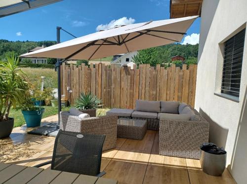 a patio with an umbrella and chairs and a couch at Belle maison avec jardin et vue montagne in Epagny Metz-Tessy