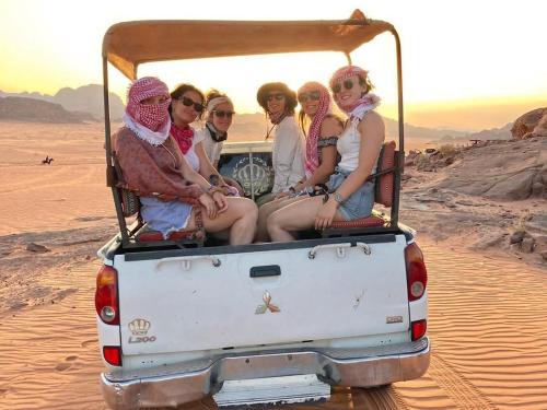 a group of women sitting in the back of a jeep in the desert at Wadi Rum Aviva camp in Wadi Rum