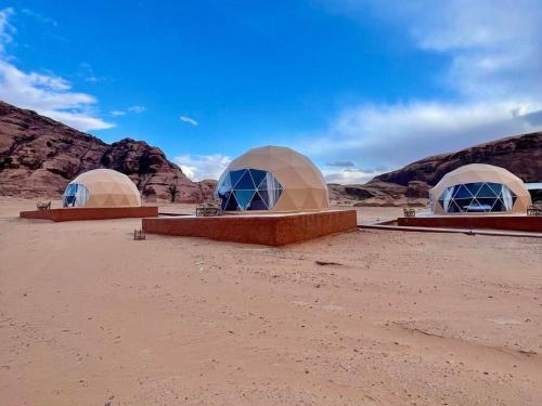three domes in the desert with mountains in the background at Wadi Rum Aviva camp in Wadi Rum