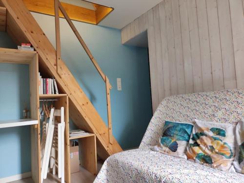 a room with a couch and a wooden staircase at Le pigeonnier d'Agnès in Jenzat