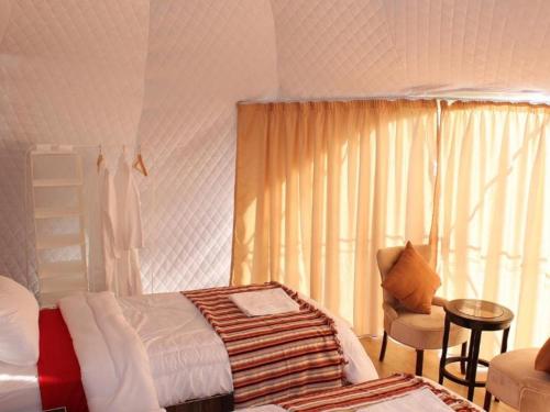 a bedroom with a bed and a chair and a window at Wadi Rum Aviva camp in Wadi Rum