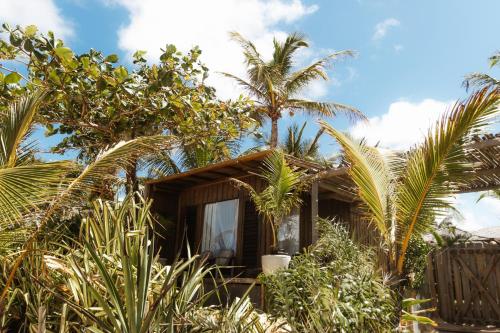 a house with palm trees in front of it at Pousada Casa Mar Pé na Areia in Caraíva