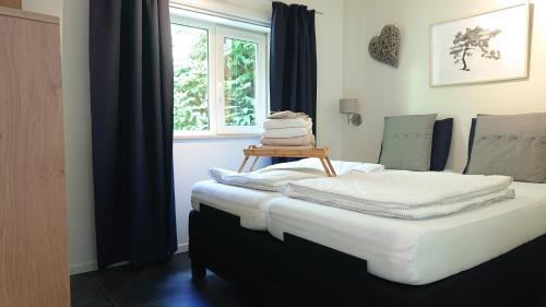 a bedroom with a bed with white sheets and a window at huisje Zilvermeeuw in Burgh Haamstede