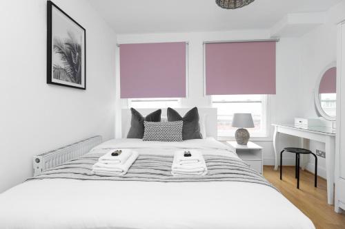 a white bedroom with a large white bed with pillows at Fantastic 2BR Flat, 3 min Shoreditch High Street in London