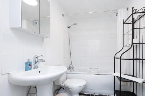 a white bathroom with a sink and a toilet at Fantastic 2BR Flat, 3 min Shoreditch High Street in London