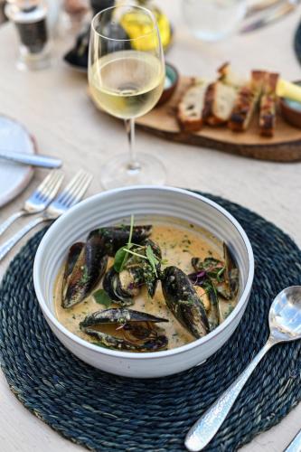 a bowl of soup with mussels and a glass of wine at Birkenhead House in Hermanus