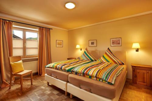 a bedroom with a bed and a chair and a window at Gästehaus am Brunnen in Bad Hindelang