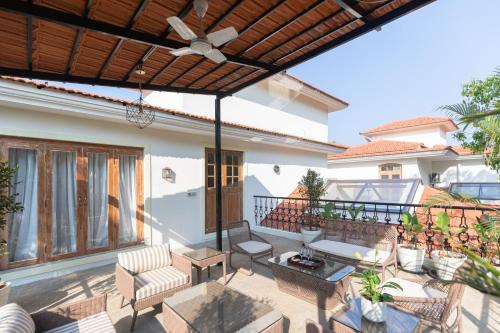 an outdoor patio with a ceiling fan and chairs at LohonoStays Colina Villa E in Vagator