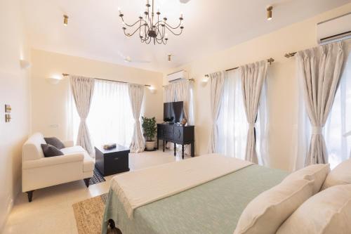 a bedroom with a bed and a couch and windows at LohonoStays Colina Villa E in Vagator