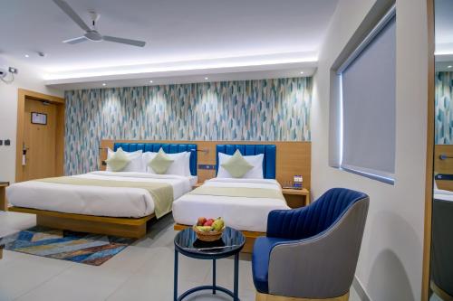 a hotel room with two beds and a chair at Cozzet Victoria Hotel in Bhubaneshwar