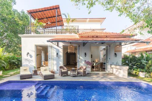 a villa with a swimming pool in front of a house at LohonoStays Colina Villa E in Vagator
