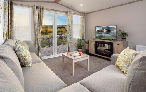 uma sala de estar com um sofá, uma televisão e uma mesa em Stonewood Premium - 2 bedroom VS04 em Tenby