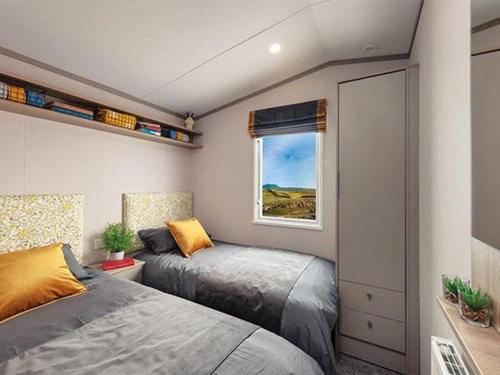 a bedroom with two beds and a window at Stonewood Premium - 2 bedroom VS04 in Tenby