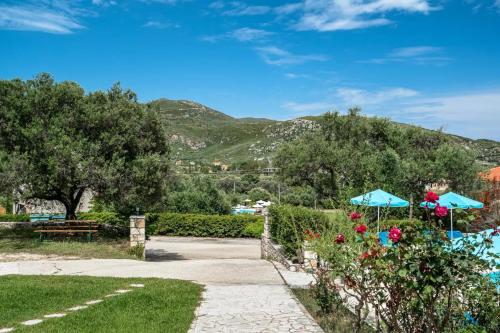 a walkway with an umbrella and flowers in a park at Anemona studio A in Katelios