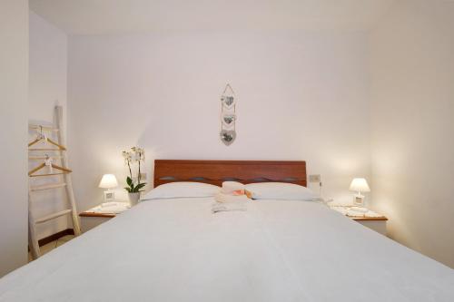 a bedroom with a large white bed with two lamps at Stella del Garda 2 con terrazza in Tignale