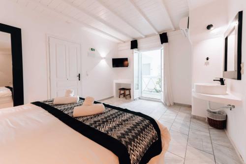 a white bedroom with a large bed and a sink at Mr & Mrs White Mykonos in Platis Yialos Mykonos
