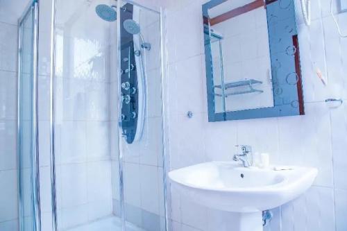 a bathroom with a sink and a shower with a mirror at Hotel Karisimbi in Kigali