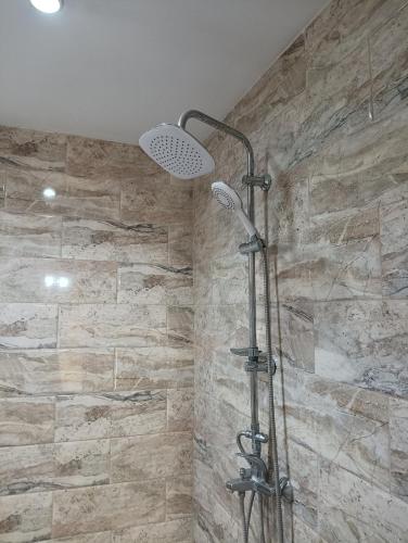 a shower in a bathroom with a stone wall at 1-ва двойна стая in Dragoman