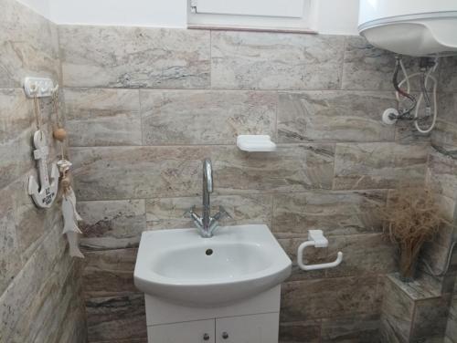 a white sink in a bathroom with a stone wall at 1-ва двойна стая in Dragoman