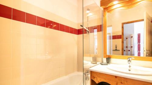 ein Badezimmer mit einem Waschbecken, einer Badewanne und einem Spiegel in der Unterkunft V du Bachat B01 - Appt lumineux 6 pers in Chamrousse