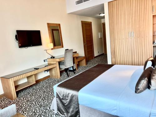 a hotel room with a bed and a desk and a television at Copthorne Hotel Sharjah in Sharjah