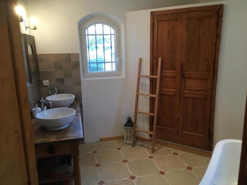 een badkamer met 2 wastafels, een raam en een ladder bij Mon Gîte en Provence in Salernes