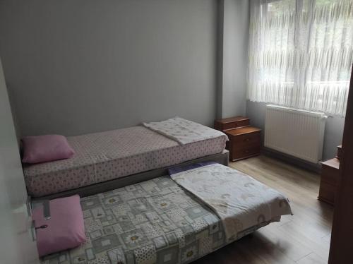 a bedroom with two beds and a window with curtains at Clifftop Bliss: Beach View, 2BR in Mudanya