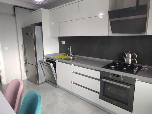 a kitchen with white cabinets and a stove and refrigerator at Clifftop Bliss: Beach View, 2BR in Mudanya