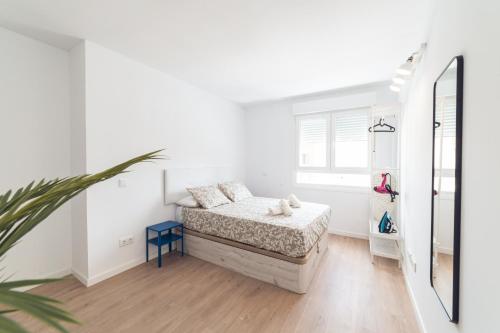 Habitación blanca con cama y espejo en ALFALFA ATICO Apartments, en Madrid