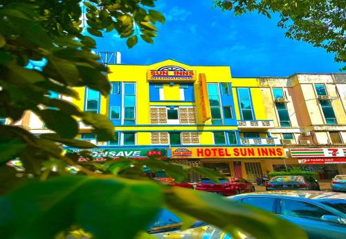 un edificio giallo con auto parcheggiate in un parcheggio di Sun Inns Hotel Kepong near Hospital Sungai Buloh a Kuala Lumpur