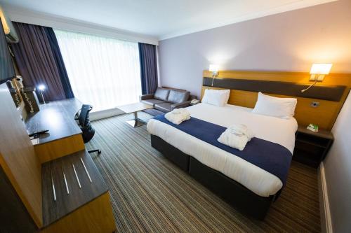 a hotel room with a large bed and a chair at Holiday Inn Newport by IHG in Newport