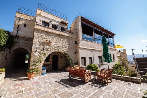 a stone building with two chairs and an umbrella at Canyon Cave Hotel in Urgup