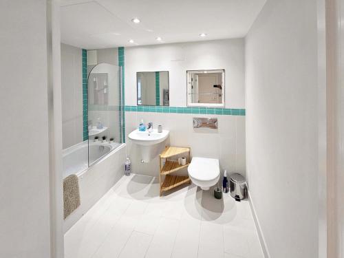 Beautiful 2 bedroom flat in Battersea في لندن: حمام أبيض مع حوض ومرحاض