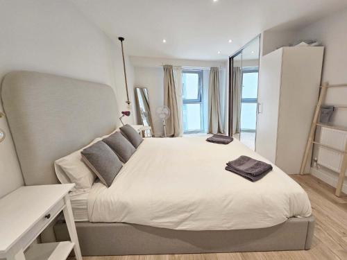 Beautiful 2 bedroom flat in Battersea في لندن: غرفة نوم مع سرير أبيض كبير مع نافذة