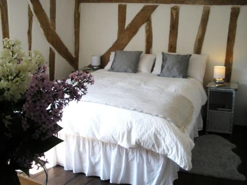 a bedroom with a white bed with two lamps and flowers at White Sheep Cottage in Peasenhall