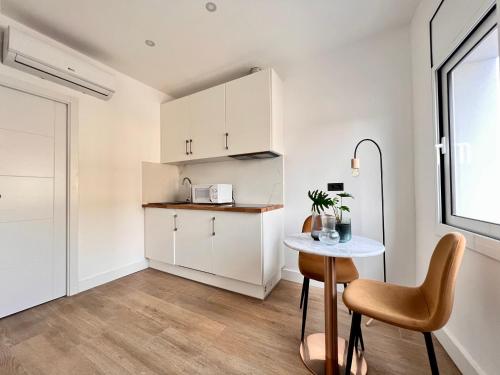 cocina con armarios blancos, mesa y ventana en Crysoyle Apartment Barcelona Next to Camp Nou en Barcelona