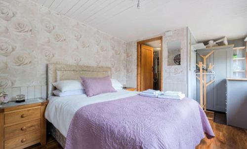 a bedroom with a large bed with a purple blanket at Clematis cabin in Hereford