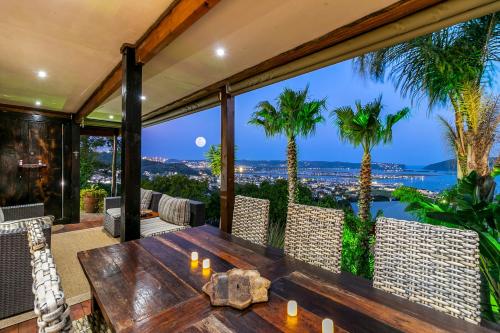 an outdoor dining room with a table and palm trees at Knysna Lodge - Self Catering Accommodation with Woodfired Hot Tub in Knysna