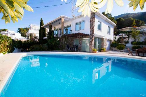 une grande piscine bleue en face d'une maison dans l'établissement Villa in Albir, à L'Alfàs del Pi