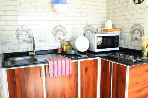 una cucina con lavandino e forno a microonde di Al khitaym guest house a Sa‘ab Banī Khamīs
