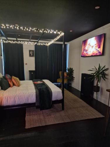 1 dormitorio con cama con dosel y luces encendidas en The Penny Black Apartment With Indoor Hot Tub en Slamannan