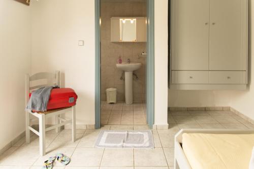 a bathroom with a sink and a red suitcase on a chair at Edgewater Studios in Kissamos