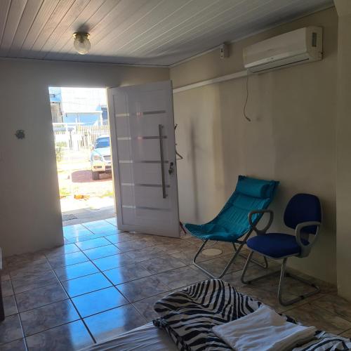 a room with a door and two chairs and a bed at Kitnet casal e apartamento com lareira e vista jardim in Esteio