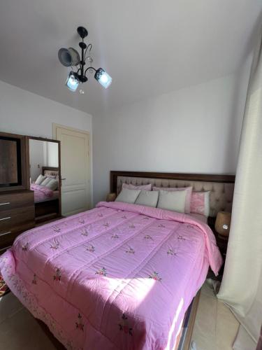 ein Schlafzimmer mit einem rosa Bett und einem Spiegel in der Unterkunft Madinaty Luxury Apartments New cairo in Madinaty