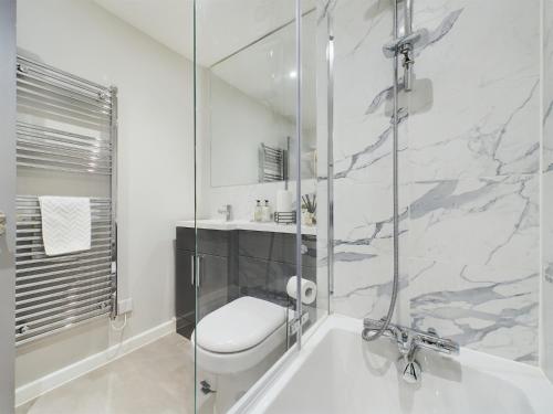 a bathroom with a toilet and a glass shower at Modern Duplex Central Free Parking Wi-Fi in Cheltenham