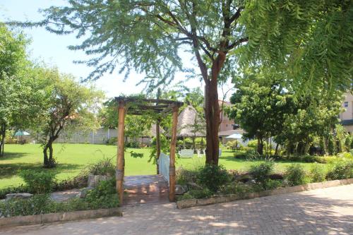 a garden with a wooden arch in a park at Pinebreeze Holiday Resort in Nyali